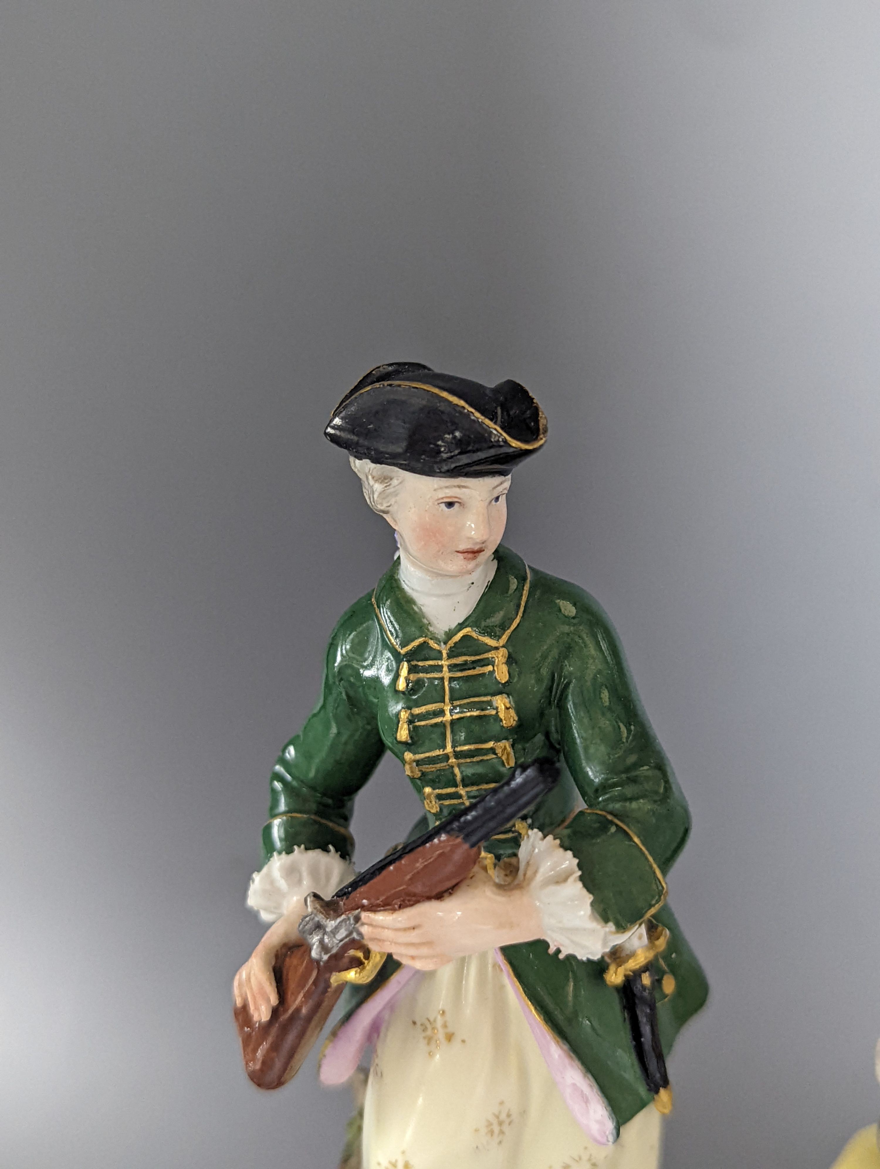 A Meissen figure of a seated man playing the bagpipes, 8.5cm., and a similar group of a huntswoman with a hound, 13cm., late 19th century, 8.5 cm and 13 cm high, some restoration